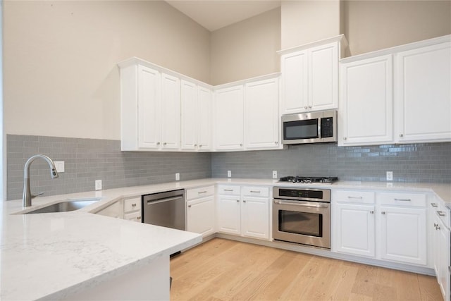 kitchen with sink, white cabinets, light wood-type flooring, and appliances with stainless steel finishes