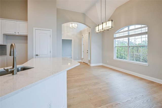 kitchen with pendant lighting, a healthy amount of sunlight, light stone countertops, and white cabinetry