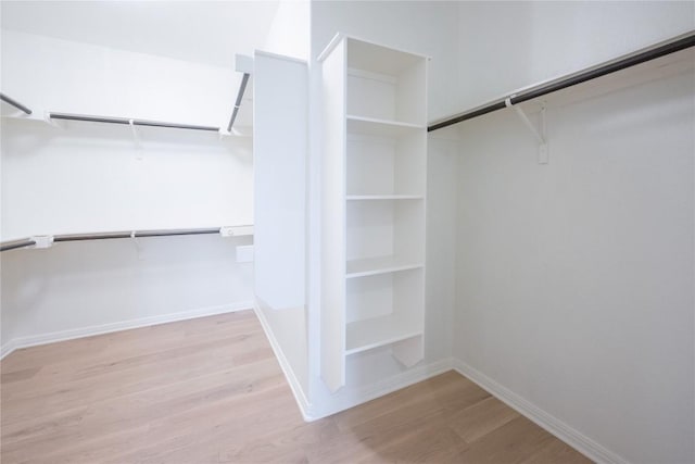 walk in closet with light hardwood / wood-style floors