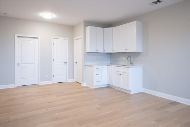 kitchen featuring white cabinets, light hardwood / wood-style floors, and sink