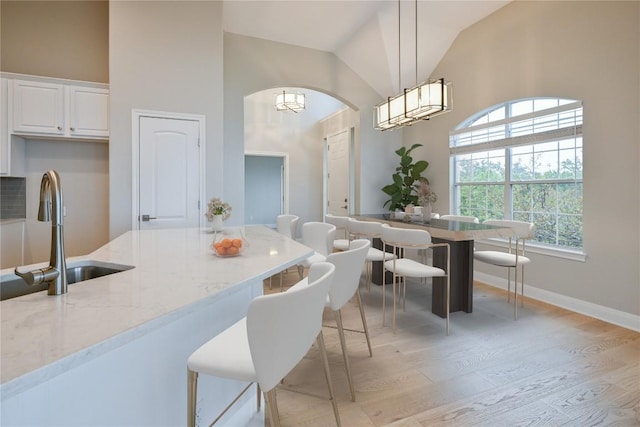 kitchen with hanging light fixtures, light stone countertops, white cabinets, and a wealth of natural light