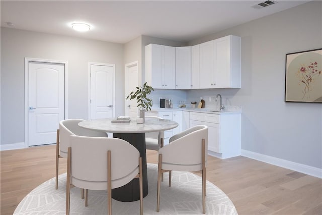 dining space with light hardwood / wood-style flooring and sink