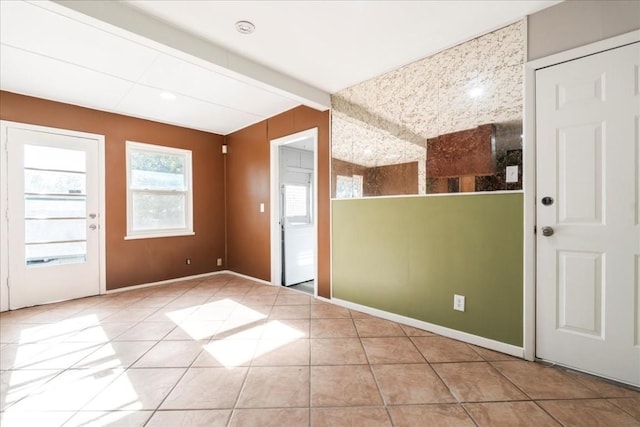 unfurnished room featuring beam ceiling and light tile patterned floors