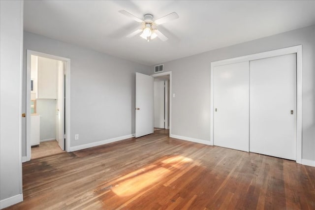 unfurnished bedroom featuring a closet, ceiling fan, hardwood / wood-style floors, and ensuite bath