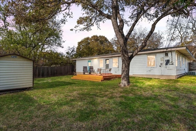 rear view of property with a lawn, a wooden deck, and a storage shed