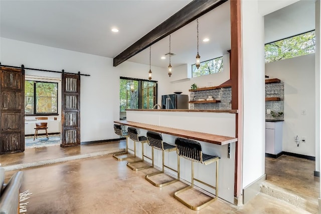 kitchen with pendant lighting, stainless steel fridge, a barn door, and a wealth of natural light