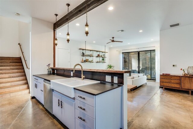 kitchen with stainless steel dishwasher, sink, hanging light fixtures, and concrete floors