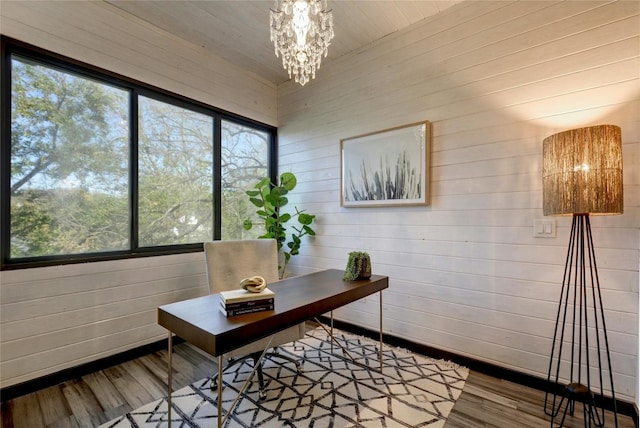 home office featuring wooden walls, hardwood / wood-style floors, and a chandelier