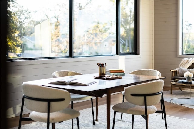 dining space with wooden walls and light hardwood / wood-style flooring