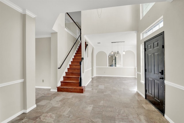 foyer with a towering ceiling and ornamental molding