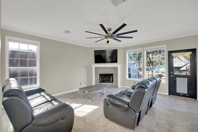 living room with a tile fireplace, crown molding, and ceiling fan