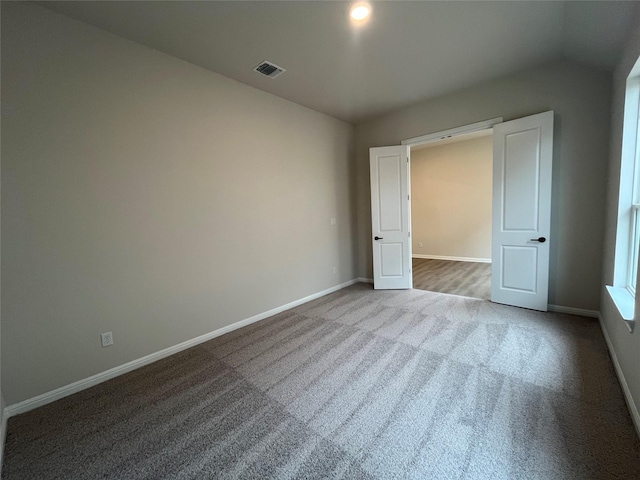 unfurnished bedroom with vaulted ceiling and carpet flooring