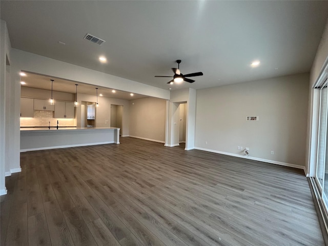 unfurnished living room with dark wood-type flooring and ceiling fan