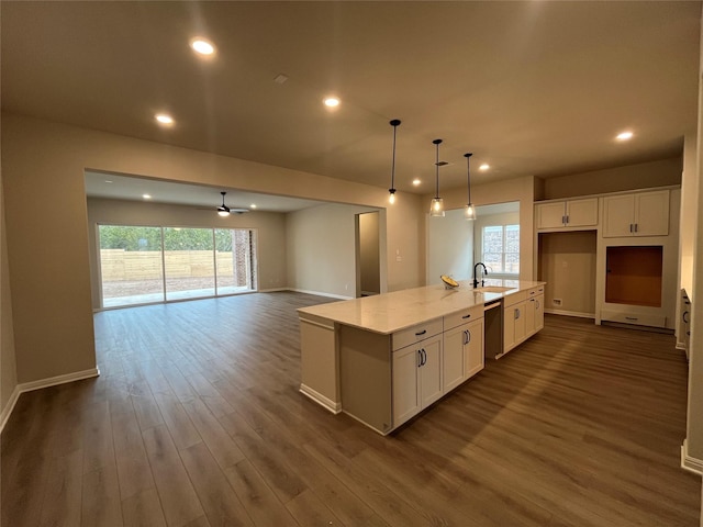 kitchen with a kitchen island with sink, pendant lighting, dishwasher, and white cabinets