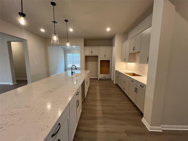 kitchen with sink, pendant lighting, white cabinets, and light stone counters