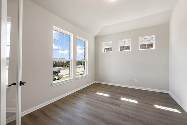 empty room with lofted ceiling, dark wood-style floors, and baseboards