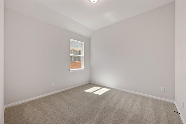 empty room featuring vaulted ceiling, carpet, and baseboards