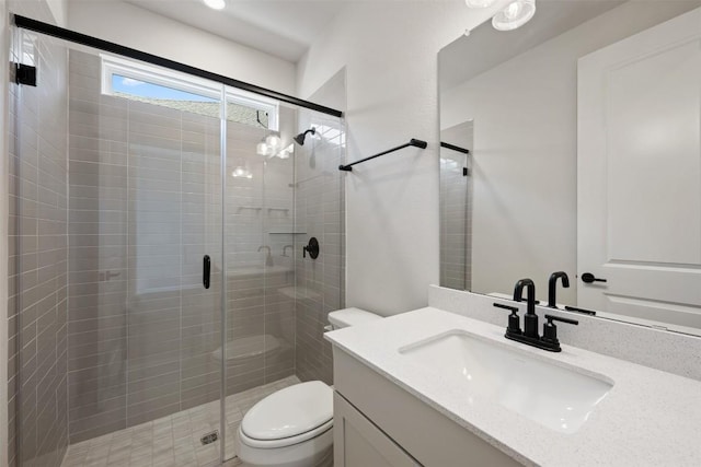 bathroom featuring toilet, a shower stall, and vanity