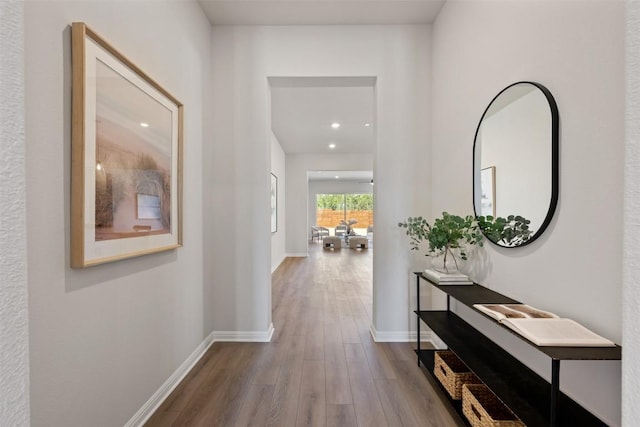 hallway with baseboards, wood finished floors, and recessed lighting