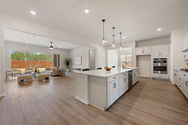 kitchen with light wood-style floors, white cabinetry, stainless steel appliances, and a sink