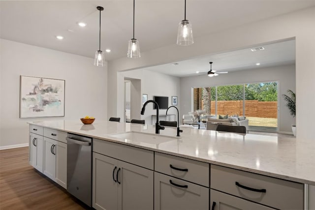 kitchen featuring light stone counters, open floor plan, a sink, and stainless steel dishwasher