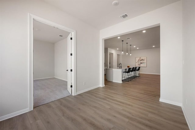 spare room with recessed lighting, visible vents, a sink, wood finished floors, and baseboards