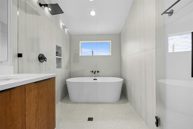 bathroom featuring vanity, a healthy amount of sunlight, tile walls, and independent shower and bath