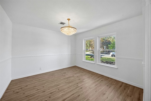 empty room featuring hardwood / wood-style floors and a chandelier