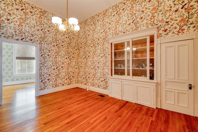 unfurnished dining area with hardwood / wood-style floors and an inviting chandelier