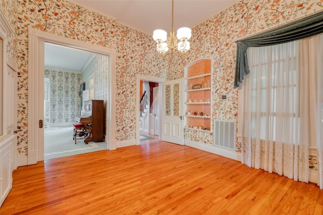 unfurnished dining area featuring crown molding, an inviting chandelier, and hardwood / wood-style flooring