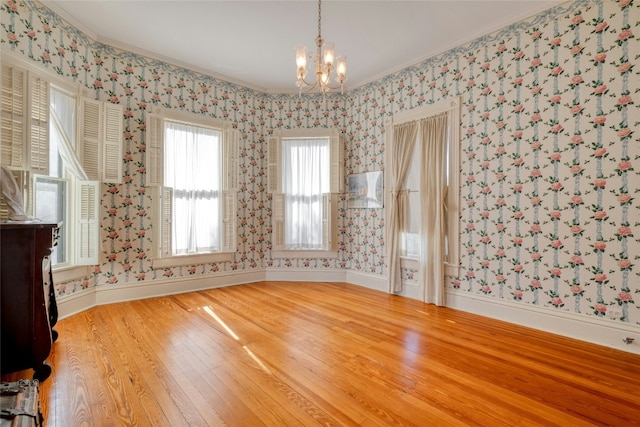 unfurnished room featuring a chandelier, hardwood / wood-style flooring, and ornamental molding