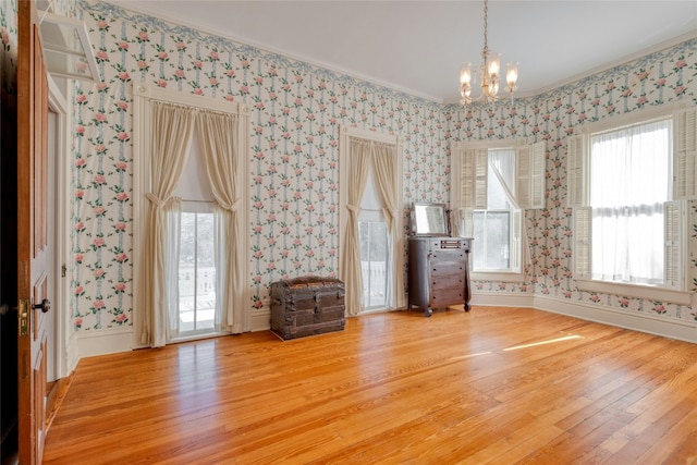 interior space featuring hardwood / wood-style floors, ornamental molding, and an inviting chandelier