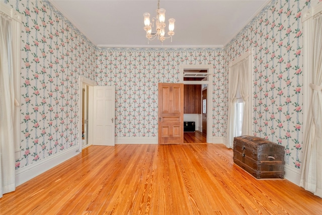 spare room featuring a notable chandelier, wood-type flooring, and ornamental molding