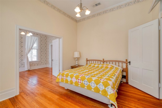 bedroom with a notable chandelier, wood-type flooring, and crown molding