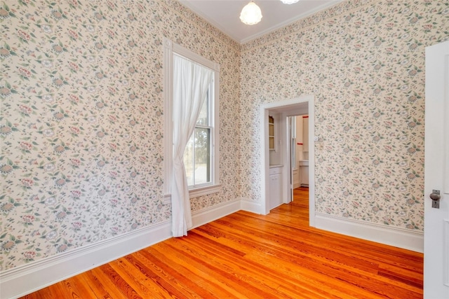 unfurnished room featuring crown molding and light wood-type flooring