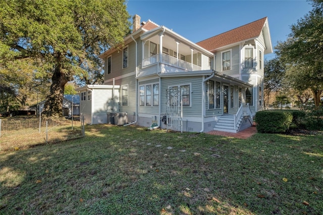 back of property with a lawn and a balcony