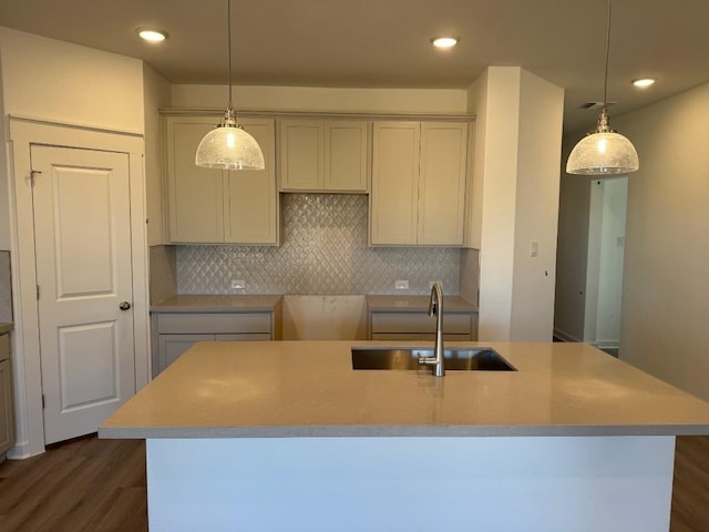 kitchen with backsplash, sink, pendant lighting, and a center island with sink