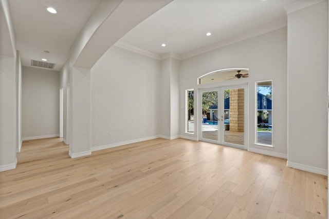 empty room with ceiling fan, french doors, ornamental molding, and light wood-type flooring