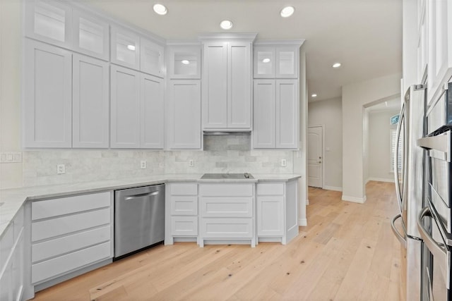 kitchen with white cabinets, light hardwood / wood-style flooring, stainless steel dishwasher, light stone countertops, and tasteful backsplash