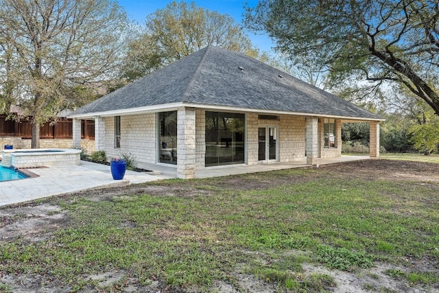 back of house with an in ground hot tub, a patio, and a lawn