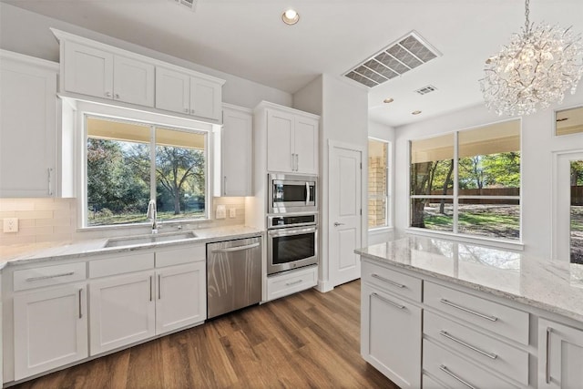 kitchen with appliances with stainless steel finishes, sink, pendant lighting, white cabinets, and dark hardwood / wood-style floors