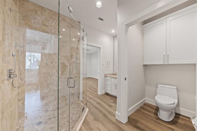 bathroom featuring toilet, vanity, a shower with shower door, and hardwood / wood-style flooring