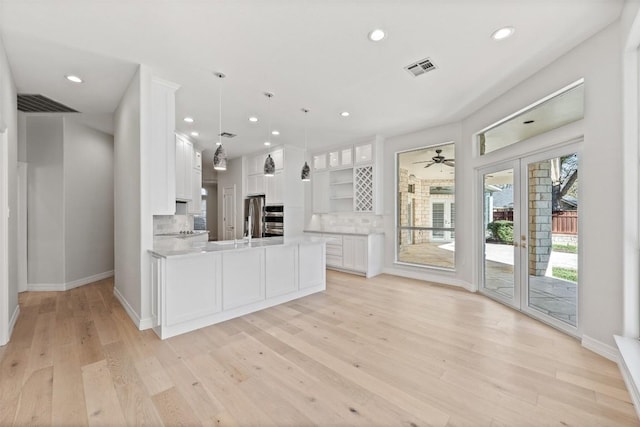 kitchen featuring decorative backsplash, decorative light fixtures, light hardwood / wood-style flooring, and white cabinetry