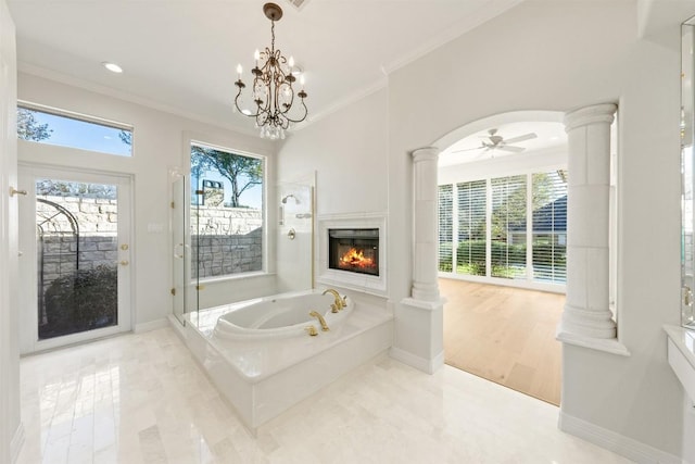 bathroom featuring ceiling fan with notable chandelier, crown molding, hardwood / wood-style flooring, ornate columns, and a tub to relax in