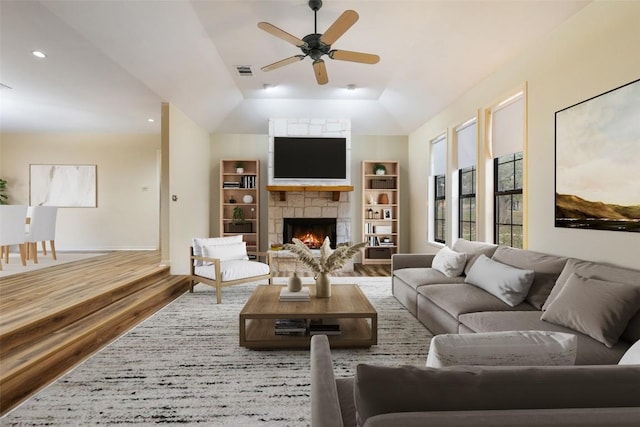 living room with hardwood / wood-style flooring, ceiling fan, lofted ceiling, and a fireplace