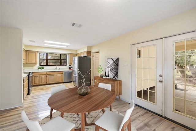 dining area with sink, french doors, and light wood-type flooring