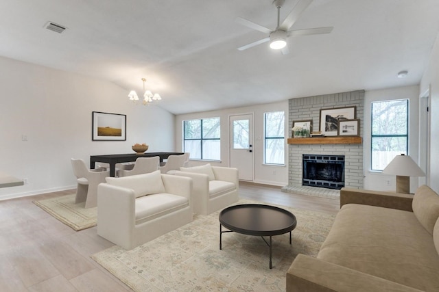 living room featuring a fireplace, ceiling fan with notable chandelier, lofted ceiling, and light wood-type flooring