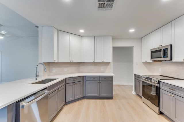 kitchen featuring sink, white cabinetry, light wood-type flooring, gray cabinetry, and stainless steel appliances