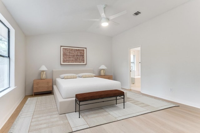 bedroom featuring ceiling fan, vaulted ceiling, connected bathroom, and light hardwood / wood-style flooring