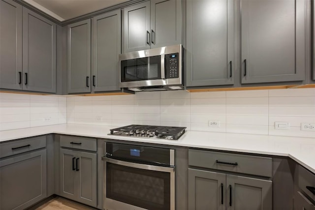 727 Palo Brea Loop, Hutto, TX 78634 - kitchen featuring appliances with stainless steel finishes, gray cabinetry, decorative backsplash, and light countertops